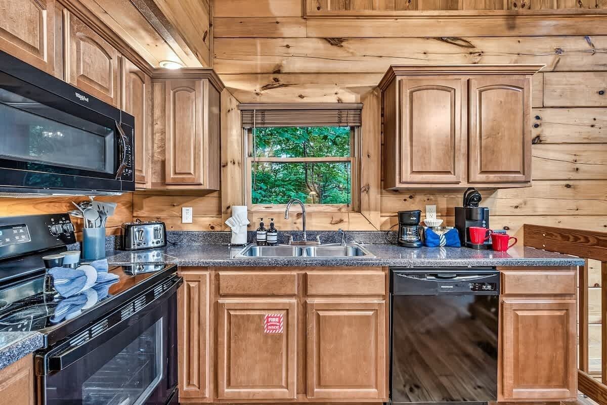 Una cocina con gabinetes de madera, microondas, estufa y lavavajillas.
