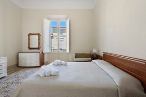 Ein Hotelzimmer mit Bett, Schminktisch, Spiegel und Fenster mit Blick auf Gebäude.