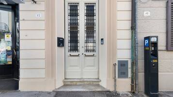 Une porte à deux battants avec un portail en métal, un parcmètre et une boîte aux lettres sur le trottoir.