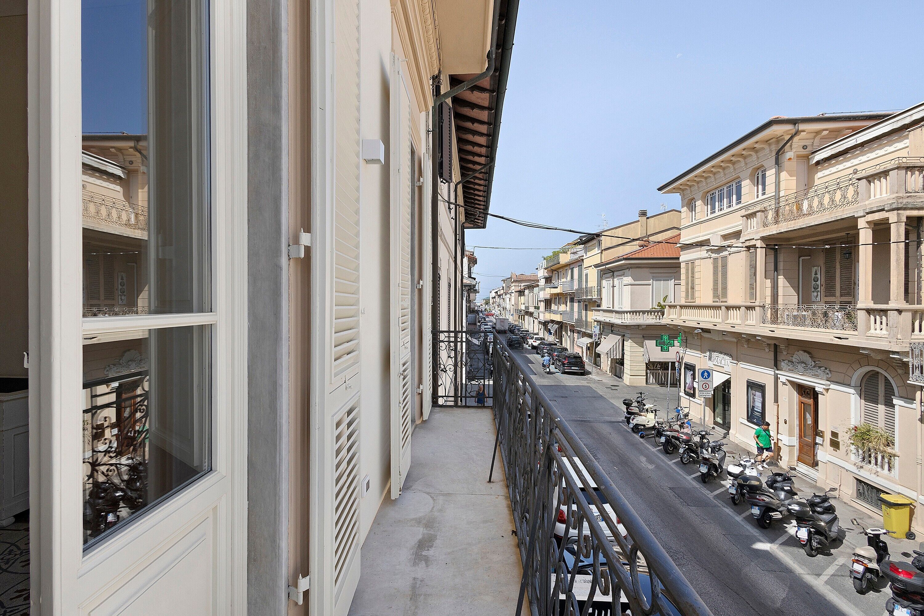 Una stretta via fiancheggiata da edifici, con una passeggiata pedonale e scooter parcheggiati.