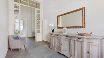 Une pièce avec un meuble blanc, un grand miroir et une chaise.