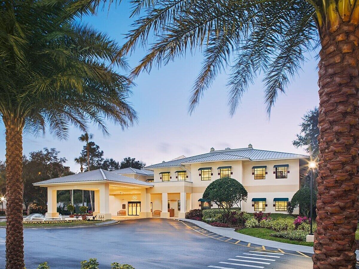 A two-story hotel with a covered entrance and a landscaped garden.