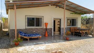 A house with a covered patio, a hammock, a table, and chairs.