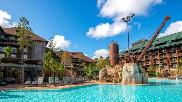 A hotel pool with clear blue water, surrounded by lounge chairs and a large water feature. - Orlando | Couples Nature Retreat | Pool + Hot Tub (Lake Buena Vista)