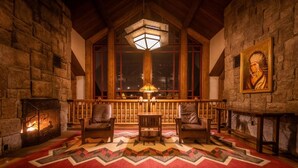A cozy room with a fireplace, wooden furniture, and a large window. - Orlando | Couples Nature Retreat | Pool + Hot Tub (Lake Buena Vista)