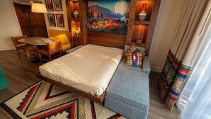 A hotel room with a bed, a seating area, a painting on the wall, and a window with curtains. - Orlando | Couples Lodge Retreat | Pool + Hot Tub (Lake Buena Vista)