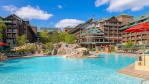 A resort with a large pool, wooden buildings, and a mountainous backdrop. - Orlando | Couples Lodge Retreat | Pool + Hot Tub (Lake Buena Vista)