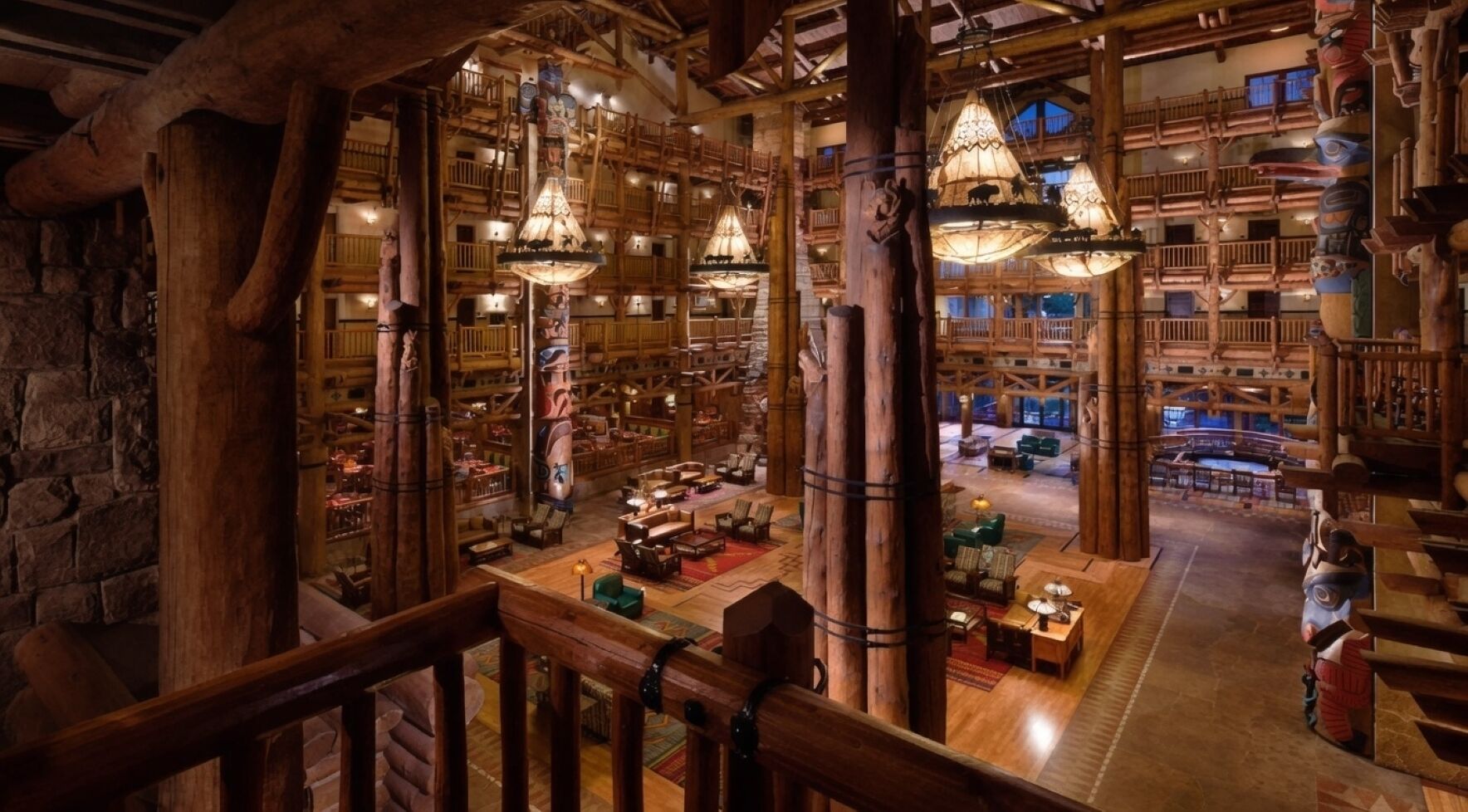 A spacious lobby with wooden architecture, multiple seating areas, and hanging light fixtures.