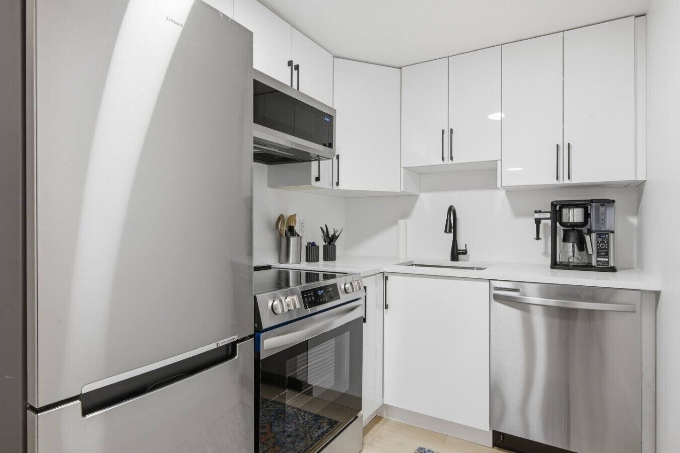 A modern kitchen with stainless steel appliances, white cabinetry, and a built-in oven.