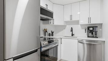 A modern kitchen with stainless steel appliances, white cabinetry, and a built-in oven.