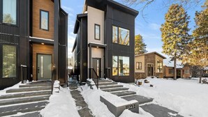 En modern flervåningsbyggnad med bostäder, där entr én och trappan upp till dörren är täckta av snö.