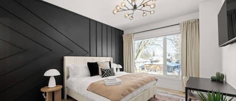 Une chambre moderne avec un grand lit, des lampes de chevet, une vue sur l’extérieur et un coin repas.