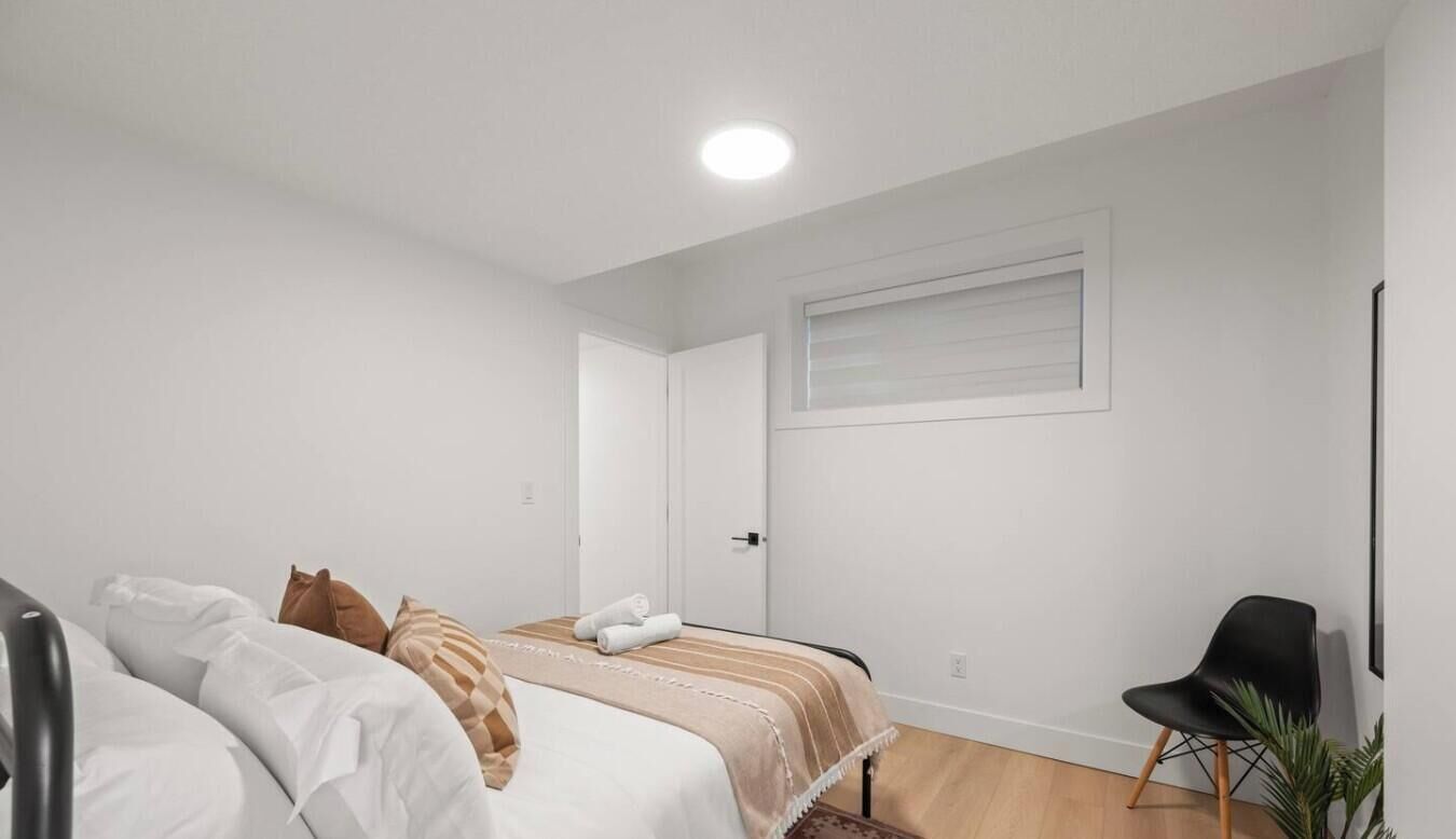 Un dormitorio con cama, una silla, una puerta y una ventana.