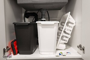 Un área de almacenamiento con dos contenedores, una bolsa roja y un objeto blanco sobre una estantería.