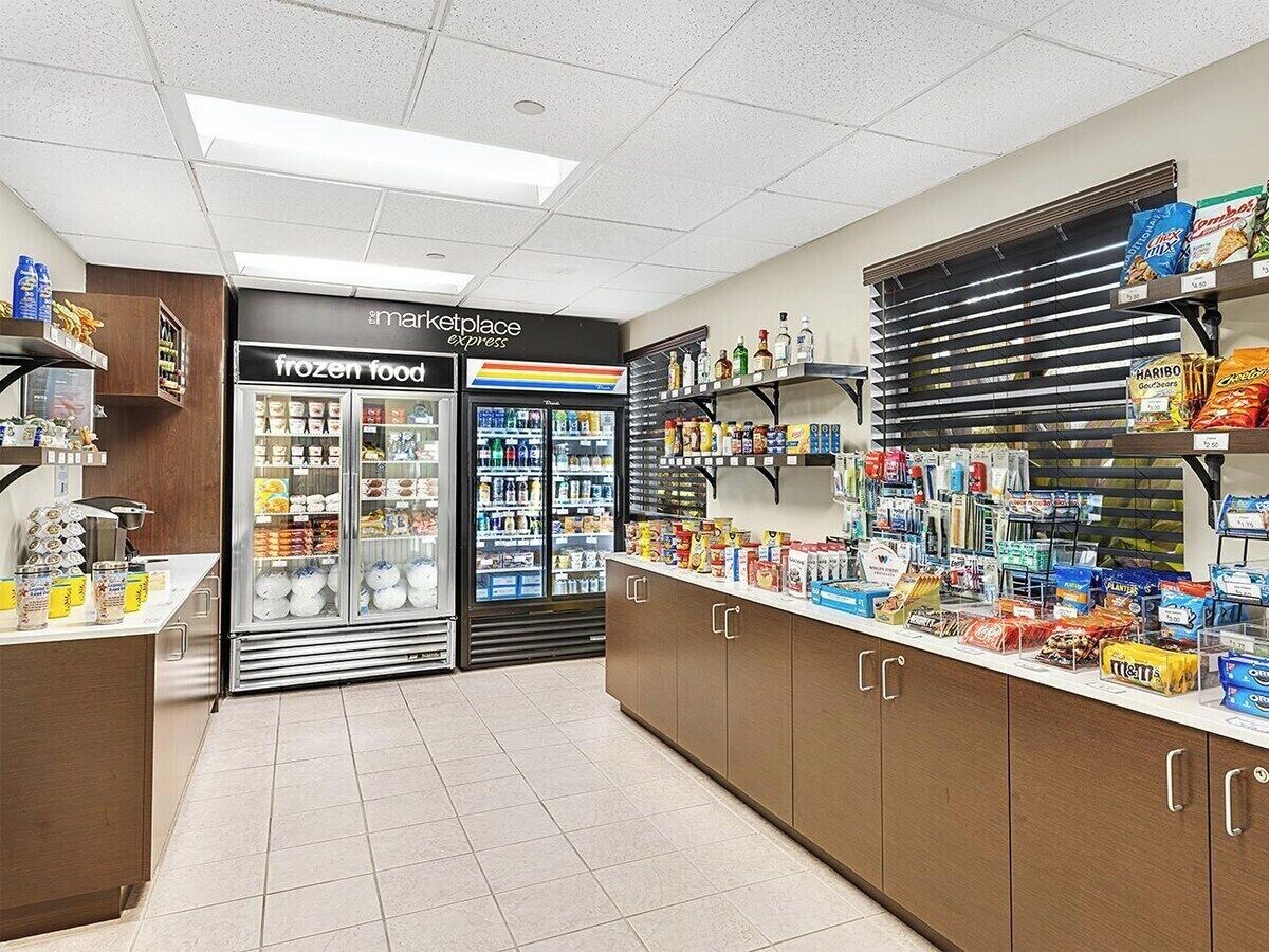 A pharmacy with a frozen food section, shelves stocked with various products, and a counter with snacks.