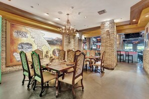 A dining area with a large mural, wooden tables, and chairs. - Sunset Over City (Fort Lauderdale)