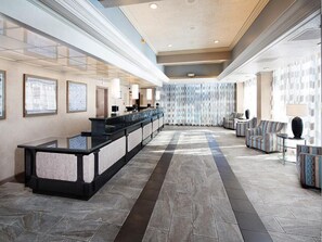 Eine geräumige Lobby mit einer Rezeption, einer Sitzecke und einer Wand mit Muster.