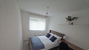 A bedroom with a bed, bedside lamps, a desk, and a chair. - Cosy City Apartment in Central London (London)
