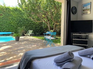 Una camera da letto con un letto, una televisione e vista su piscina e giardino.