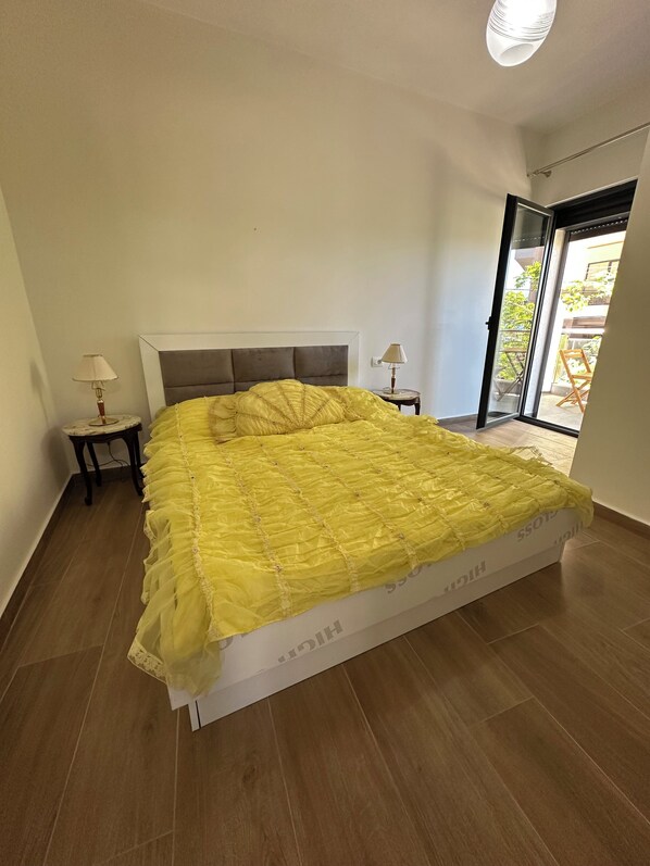 Ein Schlafzimmer mit einem großen Bett, zwei Nachttischen mit Lampen, einer Schiebetür zum Außenbereich und einer Deckenleuchte.