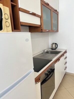 Eine Küche mit einem weißen Kühlschrank, einem Herd, einer Spüle und Holzschränken.