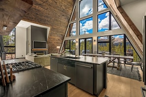 Una cocina moderna con una isla grande, electrodomésticos integrados y un comedor con vistas al exterior.