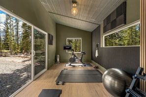 A gym with exercise equipment, a TV, and large windows.