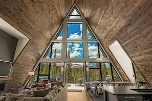 Un interior moderno con un amplio tragaluz triangular, una zona de estar acogedora y un comedor con vistas al exterior.