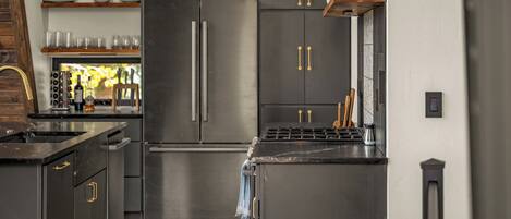 A modern kitchen with stainless steel appliances, wooden cabinets, and a built-in wine rack.