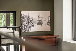 A room with a bed, a window, and a wall-mounted artwork depicting a ski lift.