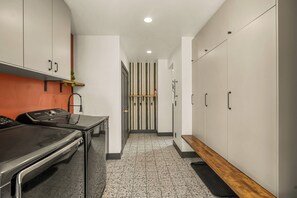 A modern kitchen with stainless steel appliances, a wooden bench, and a striped wall.