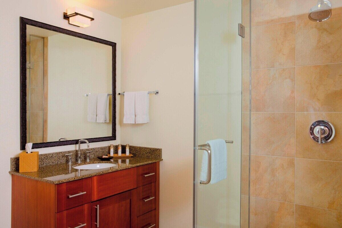 Une salle de bain avec une douche à parois de verre, un lavabo avec un miroir et des meubles en bois.