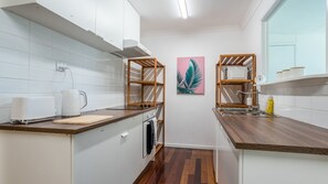 Una cocina moderna con armarios blancos, encimeras de madera, horno empotrado y estante para microondas.