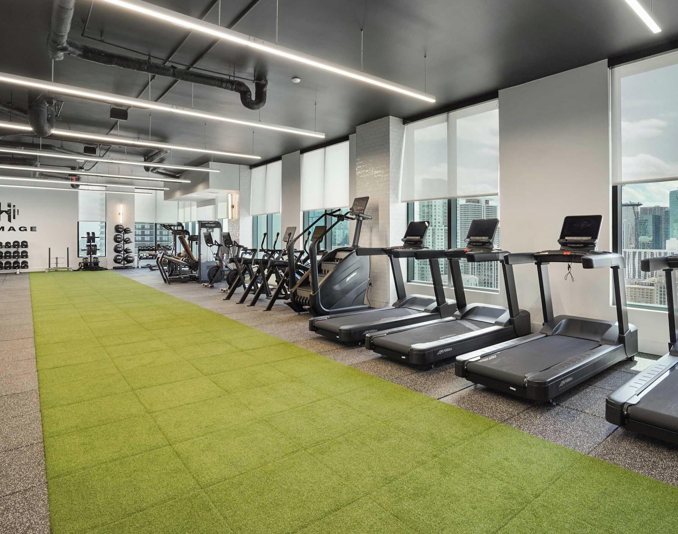 A gym with treadmills, weight machines, and a green carpeted area.