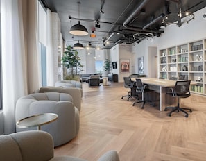 A modern office space with a long table, several chairs, a bookshelf, and a large window. - 501 First Skyline View Condos (Miami)