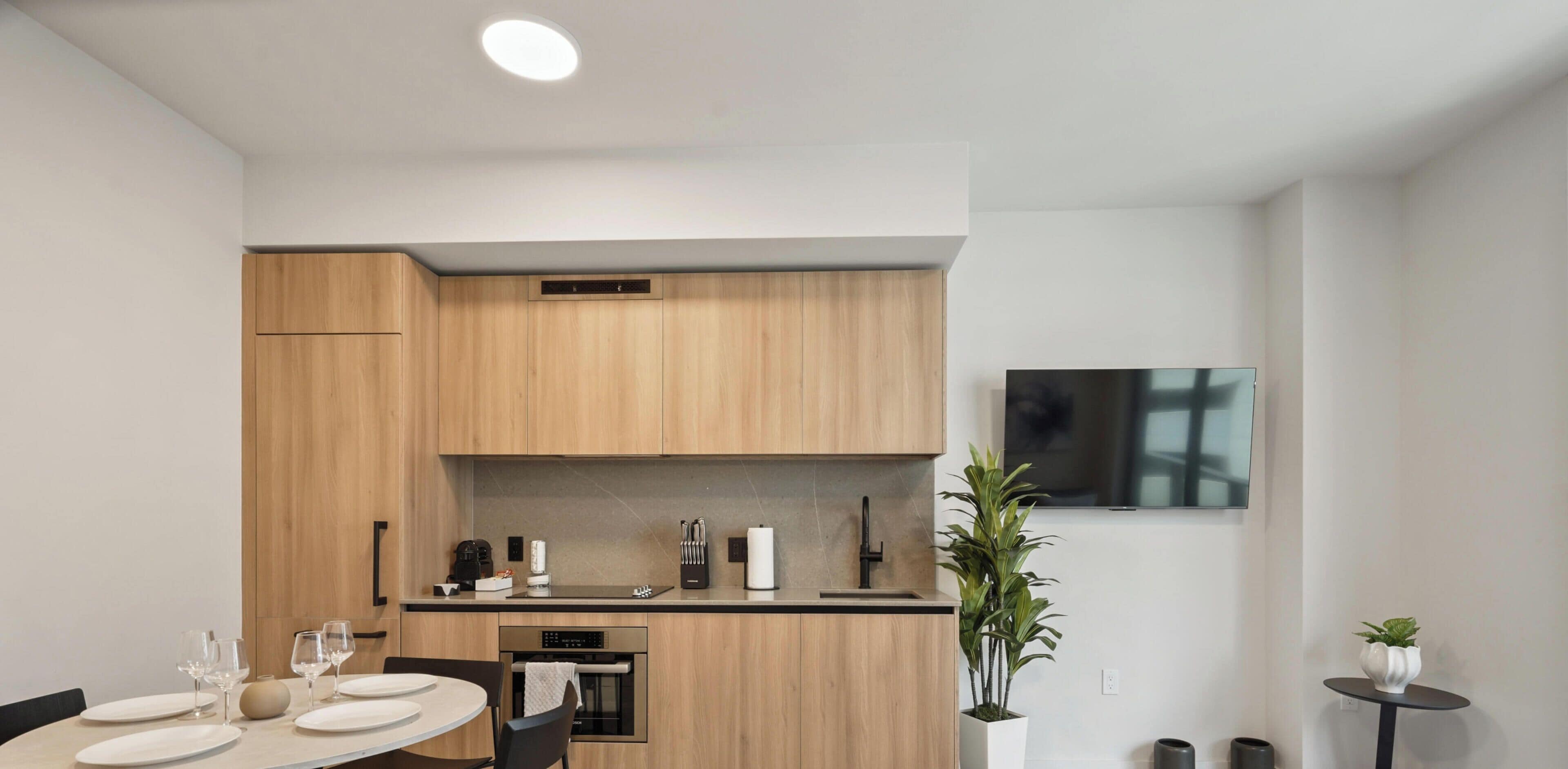 Cocina moderna con armarios de madera, horno empotrado y una zona de comedor con mesa dispuesta para dos.