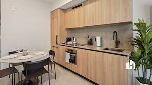Eine moderne Küche mit Holzausbau, einem Einbauofen, einer Spüle und einem Essbereich mit rundem Tisch und Stühlen.