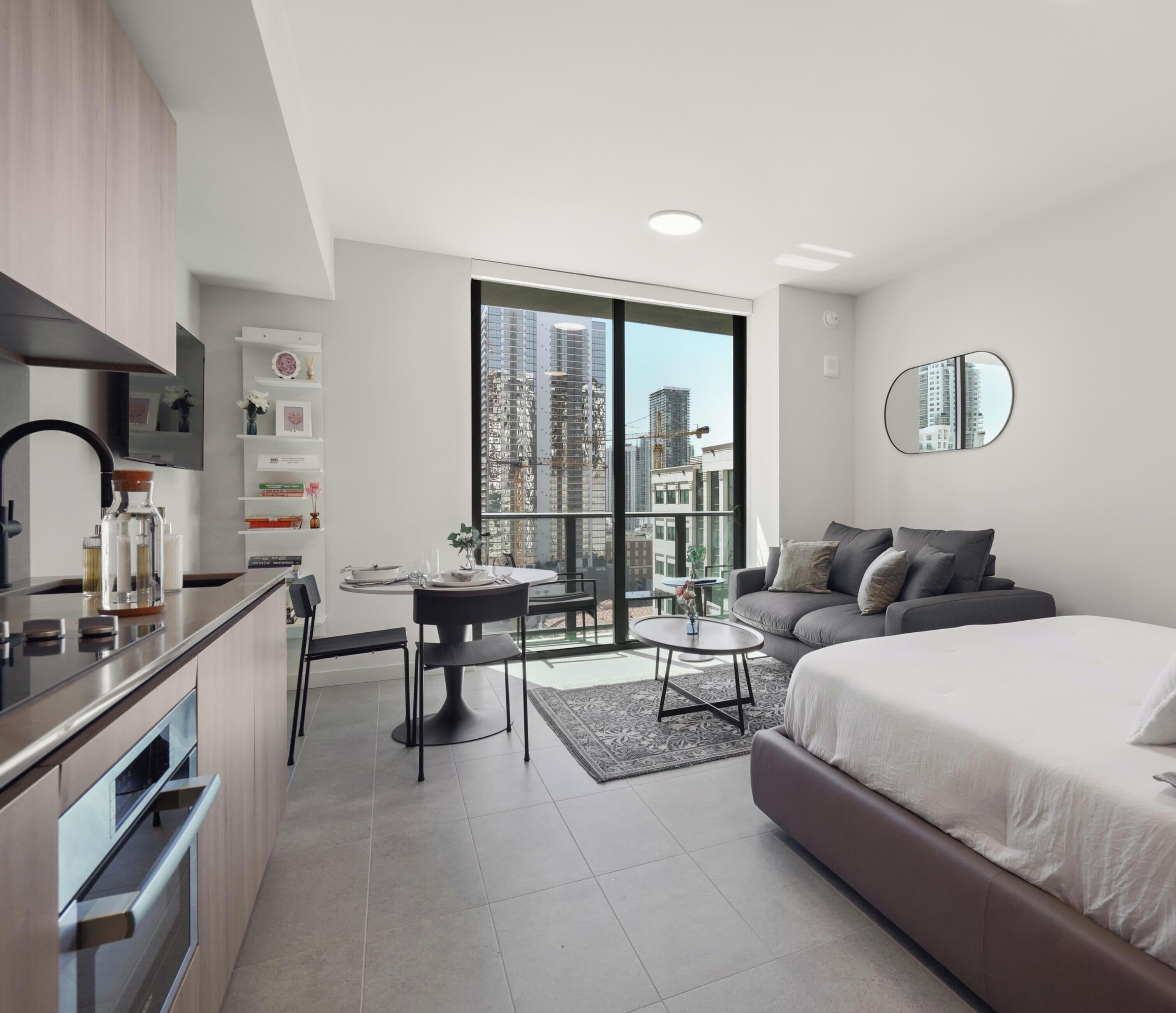 Een modern appartement met een keuken, eethoek en een groot bed.