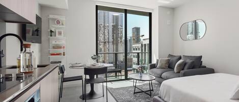 Een modern appartement met een keuken, eethoek en een groot bed.