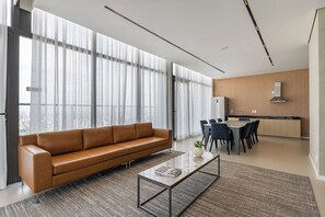 Una sala de estar moderna con un sofá de cuero, una mesa de centro y un comedor con sillas y una mesa.