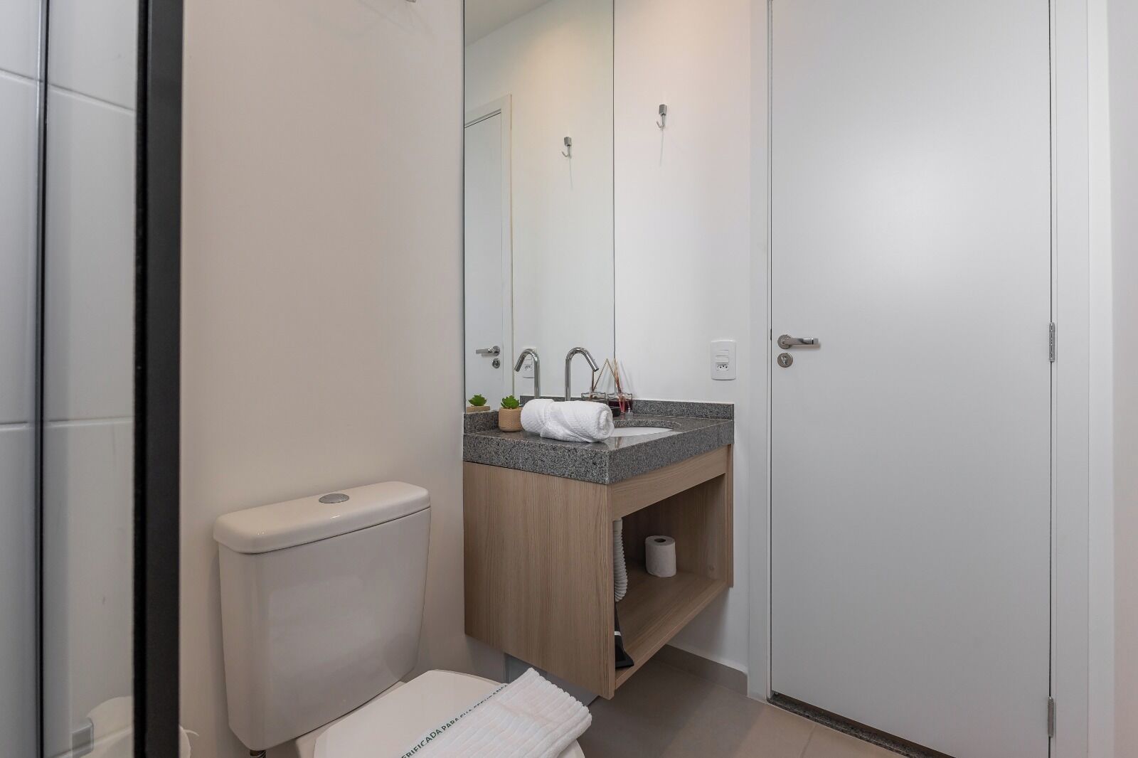 A modern bathroom with a toilet, sink, and mirror.