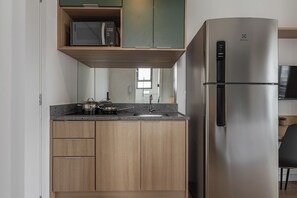 Una cocina moderna con un refrigerador de acero inoxidable, gabinetes de madera, un microondas y una encimera con una olla y una sartén.