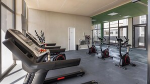 Une salle de sport équipée de tapis de course, de vélos d’appartement et d’une porte.