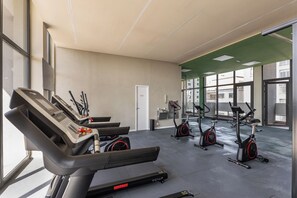 Ein Fitnessraum mit Laufbändern, Ergometer und einer Tür.