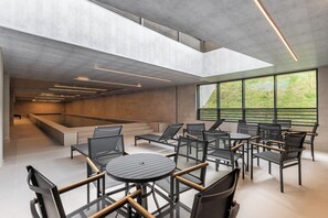 A modern interior with a pool, seating area, and large windows offering a view. - StayHome - Pinheiros - Gym & Pool (São Paulo)