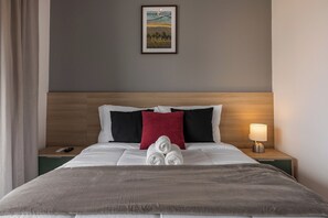 Una habitación de hotel con una cama, una mesita de noche, una lámpara y un cuadro en la pared.