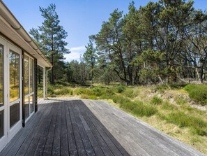A wooden deck leading to a building with large windows, surrounded by a forested area. - 4 Star Holiday Home in Albaek (Aalbaek)