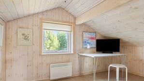 A room with wooden walls, a window, a radiator, a desk with a television, and a chair. - 4 Star Holiday Home in Albaek (Aalbaek)