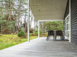 Un espace extérieur abrité doté d’une terrasse en bois, de deux chaises et d’un bâtiment avec des fenêtres.