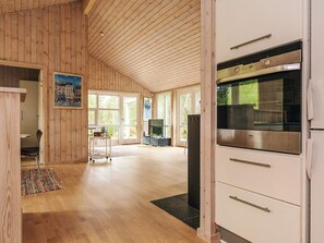 A spacious kitchen with wooden walls, a large window, and a stainless steel refrigerator.